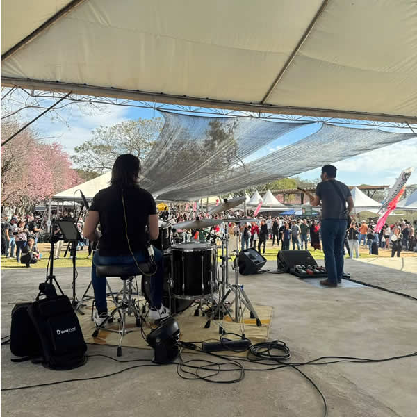 Banda se apresentando vista da parte traseira do palco em direção ao público