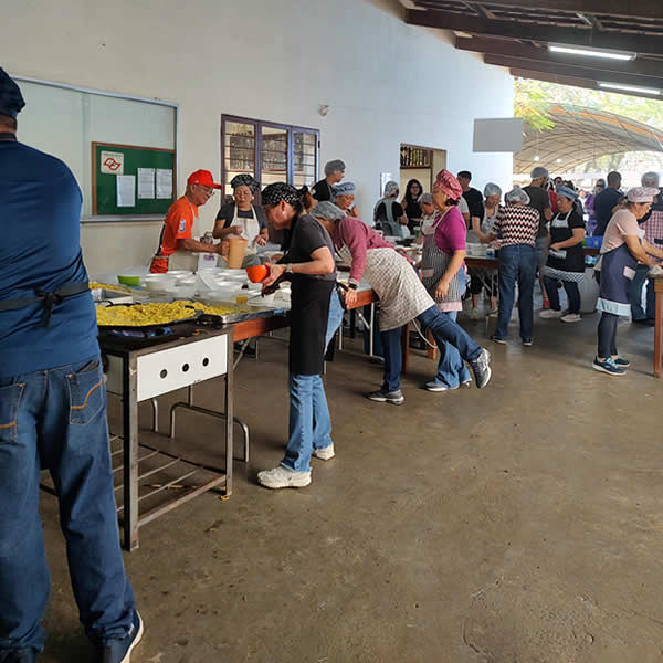 Equipe de voluntários e cozinheiros preparando os pratos típicos e yakissoba na cozinha comunitária